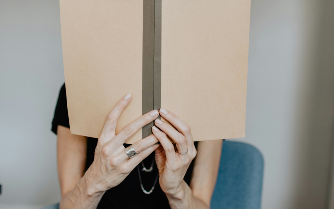 Woman holding a plain, bond book in front of her face to indicate your print book options.