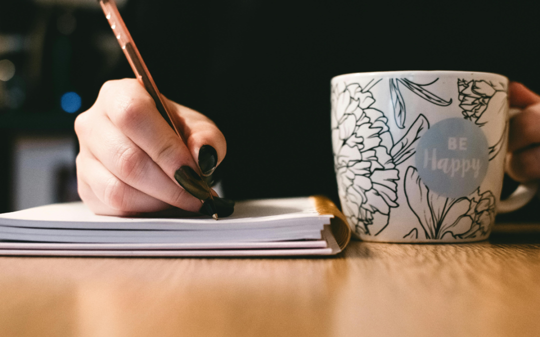 Image of a woman at a writing desk, with a pen and notebook to represent how you can improve your writing.