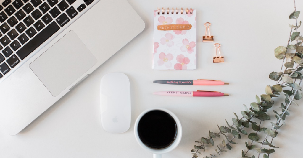 A laptop, coffee and notebooks on a work station to represent ideas for indie blog topics and your writing workspace. 